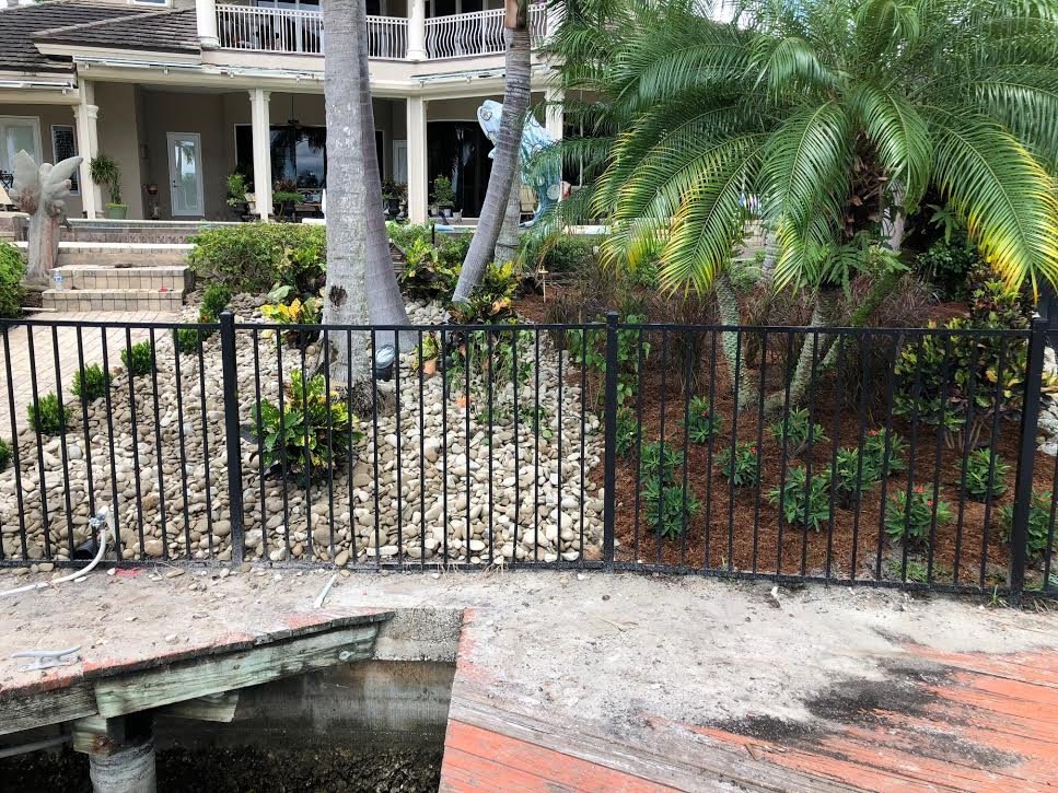 New plantings and rock along a waterfront fence line